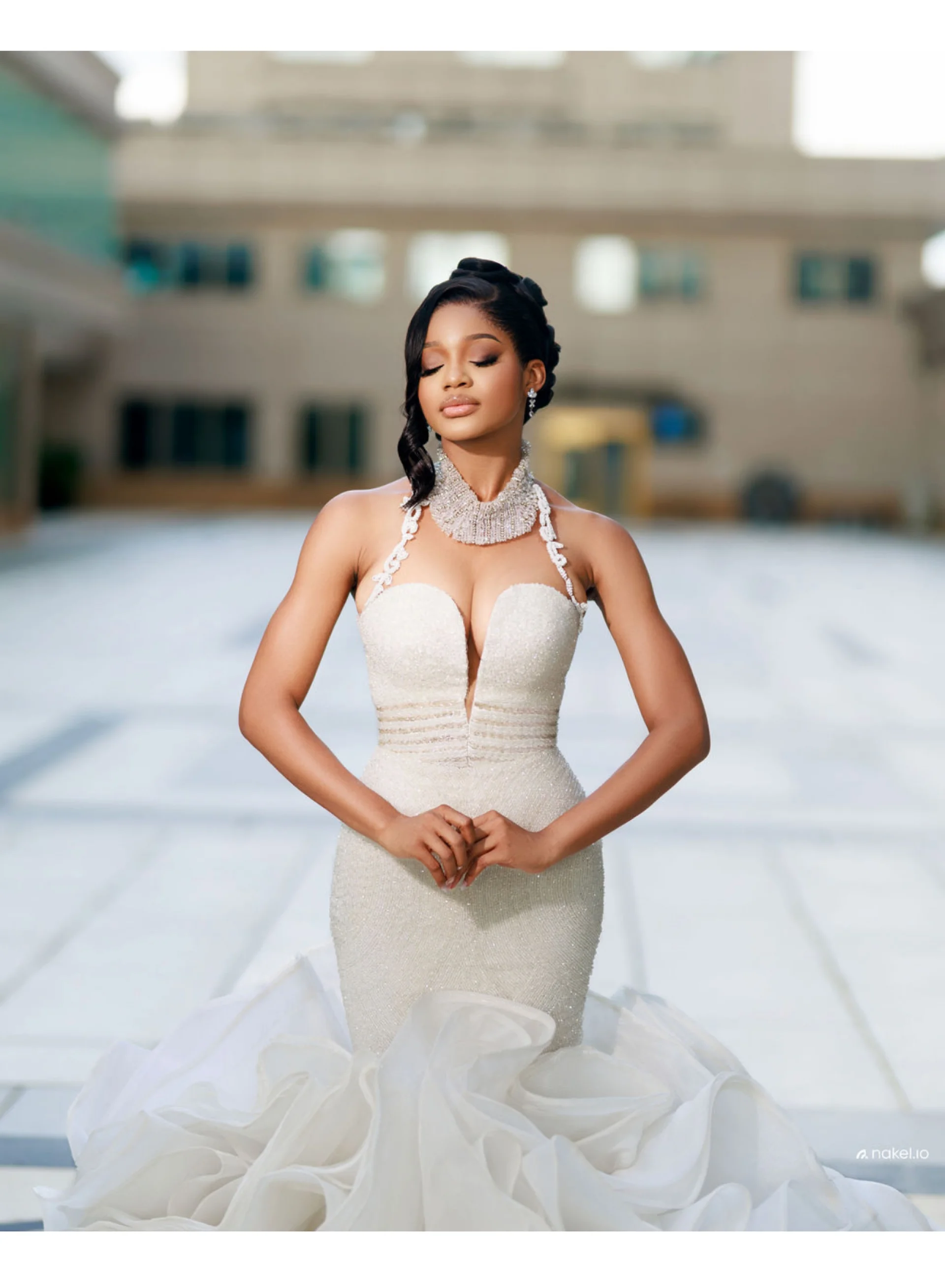 Bride in a beaded halter gown, eyes closed, courtyard backdrop